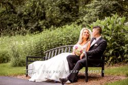 Bride and groom on a bench in a park-like setting.