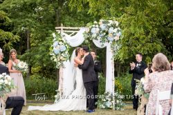 Bride and groom kissing under an arbor.